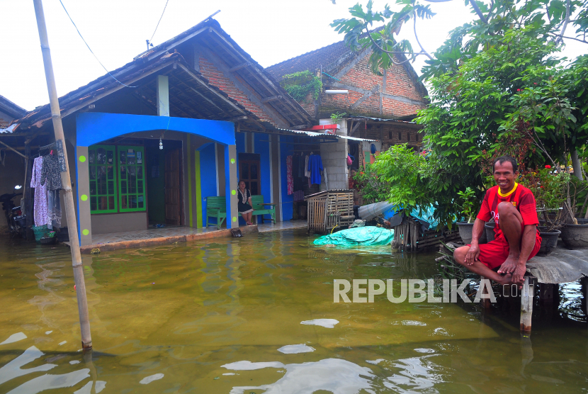 Warga duduk di halaman rumah yang tergenang banjir di Desa Karangrowo, Undaan, Kudus, Jawa Tengah, Selasa (28/2/2023). Menurut data BPBD setempat, hujan dengan intensitas tinggi sejak dua pekan terakhir mengakibatkan sebanyak 541 rumah dan 2.159 hektare sawah tergenang serta berdampak pada 4.014 KK di tujuh desa di Kecamatan Jati, Mejobo dan Undaan.  