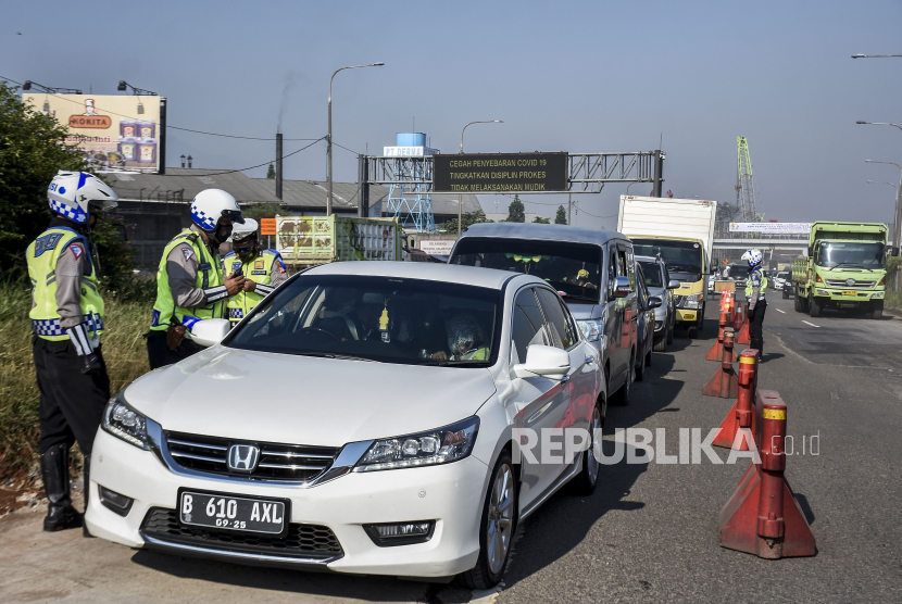 Anggota Satlantas Polresta Bandung memeriksa identitas dan surat keterangan negatif Covid-19 dari pengemudi kendaraan dengan pelat nomor dari luar Bandung di gerbang keluar Tol Cileunyi, Kabupaten Bandung, Senin (26/4). Penyekatan yang dilakukan oleh petugas gabungan dari Satlantas Polresta Bandung, Dishub Kabupaten Bandung dan Satpol PP Kabupaten Bandung tersebut merupakan bagian dari pelaksanaan larangan mudik yang resmi berlaku mulai Sabtu 24 April 2021 hingga 22 Mei 2021. Foto: Republika/Abdan Syakura