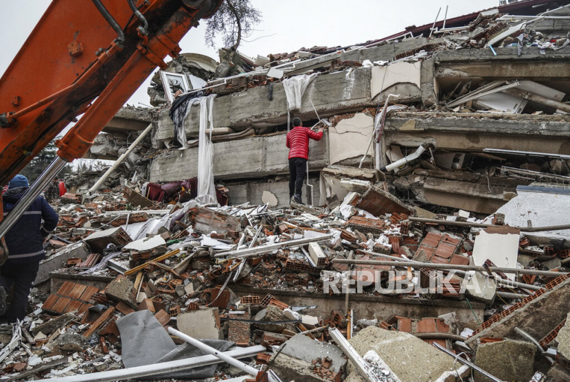  Seorang pria mencari korban gempa di puing-puing bangunan yang hancur di Gaziantep, Turki, Senin (6/2/2023). Gempa kuat telah merobohkan beberapa bangunan di tenggara Turki dan Suriah dan dikhawatirkan banyak korban jiwa.