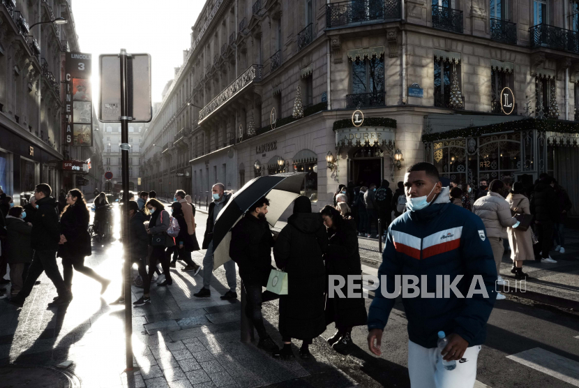 Orang-orang berjalan di jalan Champs Elysees, di Paris, Selasa, 28 Desember 2021. Pemerintah Prancis telah mengumumkan langkah-langkah baru COVID-19 dalam upaya untuk mengekang penyebaran virus. 