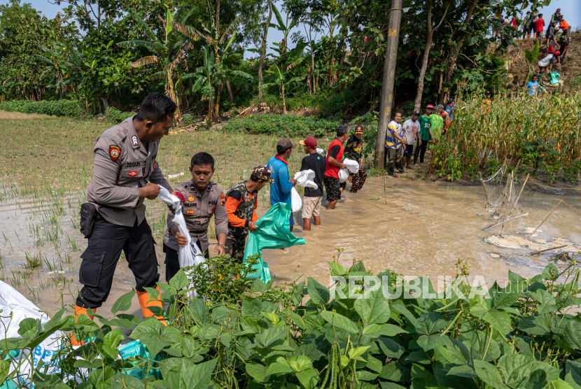 Warga membuat tanggul darurat dengan isi pasir. BPBD Mataram mendistribusikan ratusan karung kepada warga untuk membuat tanggul.