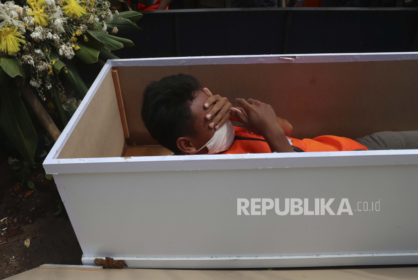  Seorang pria berbaring di dalam peti mati tiruan sebagai hukuman karena melanggar peraturan yang mengharuskan orang memakai masker di tempat umum sebagai pencegahan terhadap virus Covid-19. (ilustrasi)