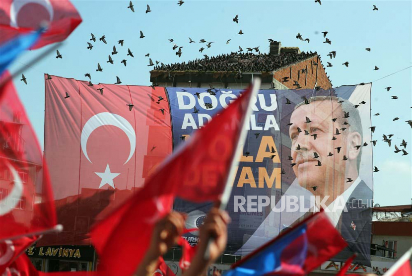 Warga Turki mengangkat poster bergambar Erdogan yang kembali memenangkan Pemilu Presiden.