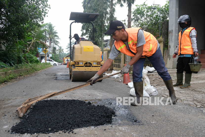 Pekerja bagian pemeliharaan dan perbaikan jalan menambal jalan berlubang di jalur Ungaran-Temanggung-Wonosobo Desa Jumo, Temanggung, Jawa Tengah. 