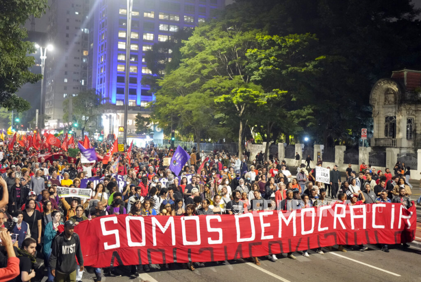  Demonstran memegang spanduk bertuliskan dalam bahasa Portugis Kami adalah Demokrasi pada protes yang menyerukan perlindungan demokrasi negara di Sao Paulo, Brasil, Senin (9/1/2023). sehari setelah pendukung mantan Presiden Jair Bolsonaro menyerbu gedung-gedung pemerintah di ibu kota.