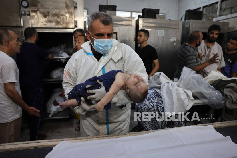Seorang petugas medis menempatkan jenazah Sila Abu Amsha yang berusia delapan bulan di atas kain kafan.