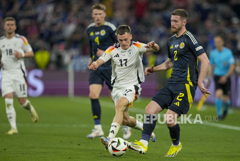 Pemain Skotlandia Anthony Ralston dan Pemain Jerman Florian Wirtz berebut bola saat pertandingan Grup A antara Jerman dan Skotlandia pada turnamen sepak bola Euro 2024 di Munich, Jerman, Jumat, 14 Juni 2024.Timnas Jerman menang telak 5-1 atas Skotlandia pada pertandingan pembuka Euro 2024.