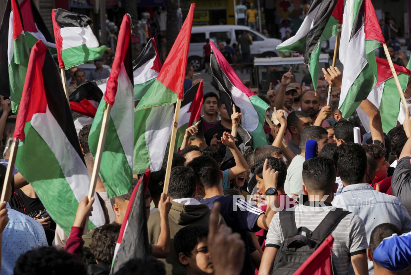 Pendukung Hamas mengibarkan bendera Palestina selama protes terhadap pawai bendera Israel untuk menandai Hari Yerusalem, hari libur Israel merayakan penaklukan Kota Tua Yerusalem selama perang Timur Tengah 1967, di kamp pengungsi Jebaliya, Jalur Gaza utara, Ahad, 29 Mei , 2022.