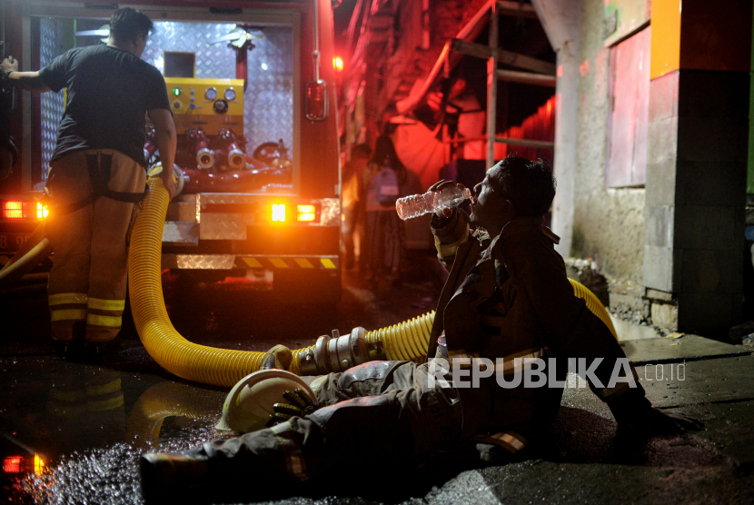  Sejumlah petugas tengah beristirahat sejenak di tengah upaya memadamkan api yang membakar rumah warga imbas kebakaran Depo Pertamina Plumpang,kawasan Jalan Koramil, Rawa Badak Selatan, Koja, Jakarta Utara, Jumat (3/3/2023).