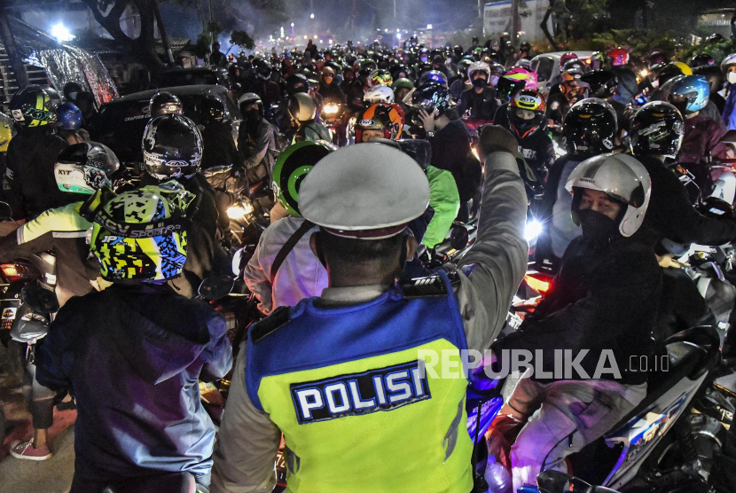 Petugas Kepolisian menghalau pemudik motor yang melawan arah untuk menghindari posko penyekatan mudik di Kedungwaringin, Kabupaten Bekasi, Jawa Barat, Minggu (9/5/2021). 