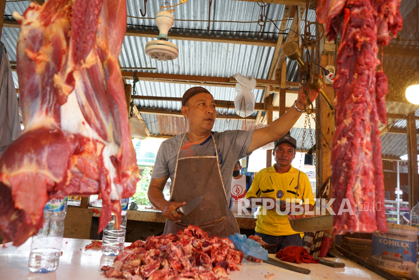 Pedagang memotong daging sapi pesanan pembeli di pasar. 