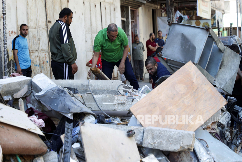 Orang-orang memeriksa puing-puing bangunan Abu Hussein yang hancur akibat serangan udara Israel dini hari, di Kota Gaza, Rabu, 19 Mei 2021.