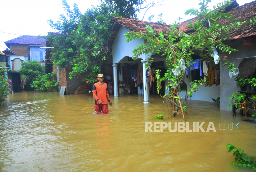 Seorang warga melewati jalan yang terendam banjir di Desa Temulus, Mejobo, Kudus, Jawa Tengah, Ahad (1/1/2023). Banjir akibat intensitas hujan yang tinggi sejak Jumat (30/12/2022) di wilayah tersebut menyebabkan belasan ribu rumah di 16 desa dari empat kecamatan terendam. 