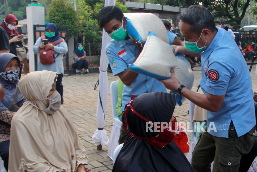 Petugas Kemensos memberikan beras kepada warga penerima paket sembako bantuan pemerintah tahap lima kepada warga di Rawa Buntu, Tangerang Selatan, Banten.