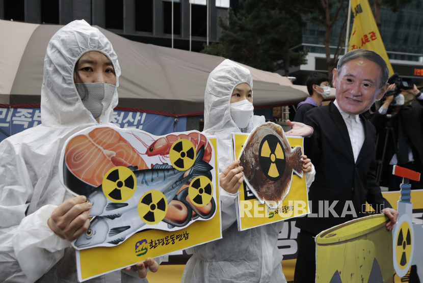 Aktivis lingkungan yang mengenakan topeng Perdana Menteri Jepang Yoshihide Suga dan pakaian pelindung tampil untuk mengecam keputusan pemerintah Jepang tentang air Fukushima, dekat kedutaan Jepang di Seoul, Korea Selatan, Selasa, 13 April 2021. 