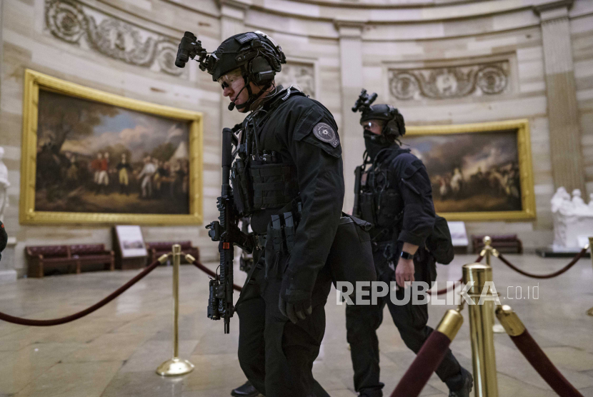 Anggota Tim Counter Assault Dinas Rahasia AS berjalan melalui Rotunda ketika mereka dan pasukan polisi federal lainnya menanggapi ketika pengunjuk rasa yang kejam yang setia kepada Presiden Donald Trump menyerbu Capitol AS hari ini, di Capitol di Washington, Rabu, 6 Januari 2021.
