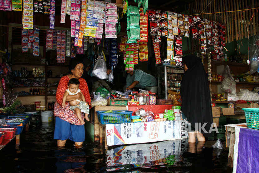 Warga membeli bahan pokok di toko yang terendam banjir di Palangka Raya, Kalimantan Tengah. Pemkot setempat menetapkan status siaga banjir selama sepekan.
