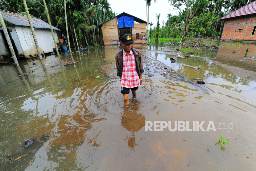 Warga berjalan melintasi kawasan permukiman yang terendam banjir. 