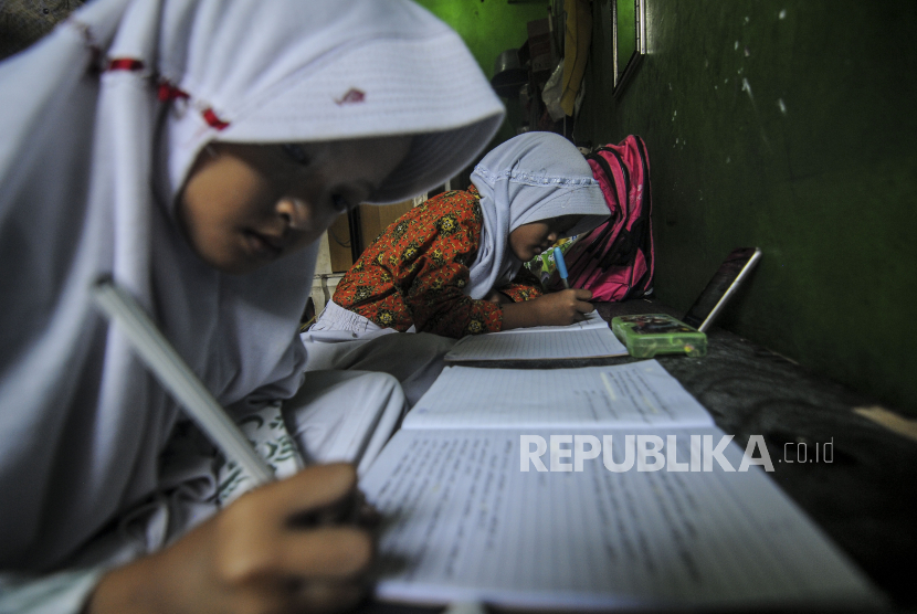 Siswa MI As-Shiddiqin Achafa (8) dan Maudi (8) saat mengerjakan tugas melalui gawainya di kawasan Kalibaru, Cilincing, Jakarta, Selasa (21/7).