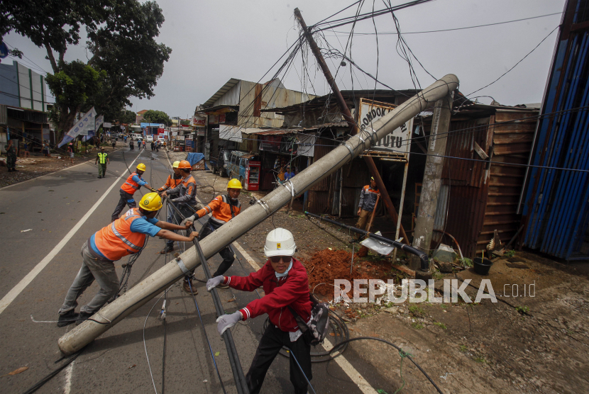 Sejumlah petugas mengevakuasi tiang listrik yang roboh di Jalan Raya Kalimulya, Cilodong, Depok, Jawa Barat, Kamis (9/2/2023). BMKG menjelaskan hujan dan angin kencang karena pola angin di perairan selatan Jawa.