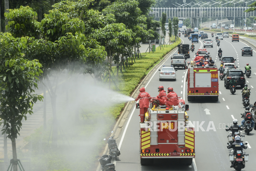 Petugas Damkar DKI Jakarta menyemprotkan cairan disinfektan di kawasan Sudirman, Jakarta