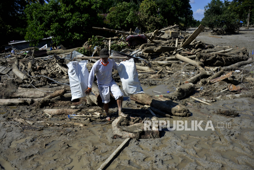 Warga mengangkat barang miliknya melewati material lumpur dan potongan batang pohon di Desa Radda, Kabupaten Luwu Utara, Sulawesi Selatan, Sabtu (18/7/2020). Pascabanjir bandang sejumlah warga yang terdampak mulai mengambil barangnya yang masih bisa digunakan. 