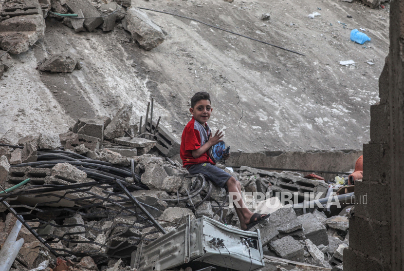 Seorang bocah Palestina duduk di antara puing-puing rumah yang hancur akibat serangan udara Israel di Kota Gaza, Kamis (19/5). (ilustrasi)