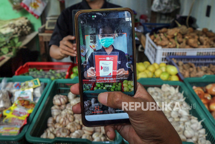 Warga memindai QRIS  saat berbelanja di Pasar Tradisional Cibinong, Kabupaten Bogor, Jawa Barat, Selasa (23/11/2021). BPS mencatat pengeluarkan penduduk Kabupaten Bogor pada 2020 menurun dibandingkan 2019 akibat pandemi Covid-19.