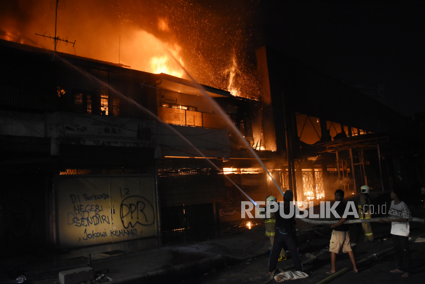Petugas Pemadam Kebakaran dibantu warga memadamkan api yang menghanguskan bangunan di kawasan Senen, Jakarta, Kamis (8/10/2020) malam. Menurut warga sejumlah bangunan toko dan bekas gedung bioskop Megaria tersebut dibakar massa saat berunjuk rasa menolak pengesahan Omnibus Law UU Cipta Kerja. 