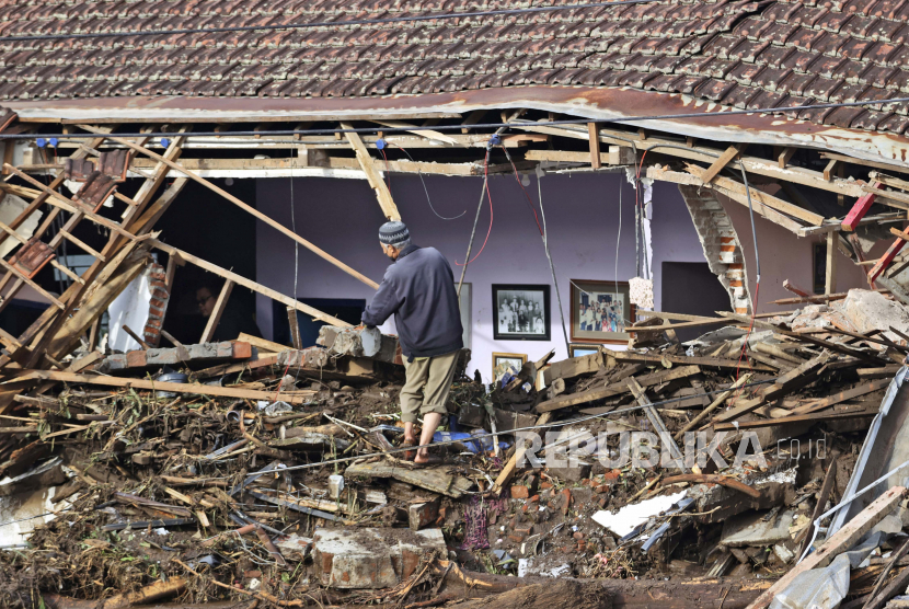 Seorang pria memeriksa rumah yang rusak akibat banjir bandang di Desa Bulukerto, Batu, Jawa Timur, Jumat, 5 November 2021.