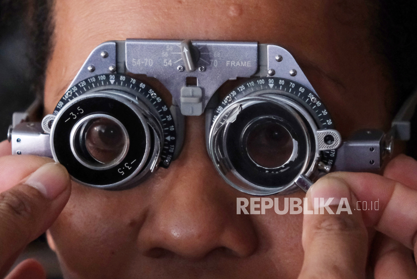 Dokter memasangkan lensa kacamata minus saat memeriksa kondisi mata seorang warga.