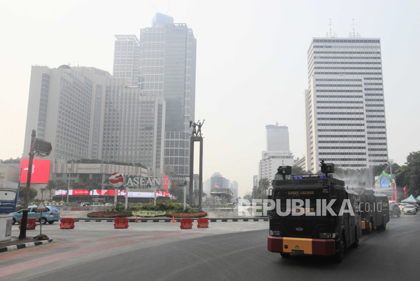 Mobil kepolisian menyemprotkan air di kawasan Bundaran HI, Jakarta, Rabu (23/8/2023). Penyemprotan di sekitar jalan protokol tersebut sebagai upaya untuk membersihkan debu-debu yang bertebaran di jalanan akibat polusi udara.
