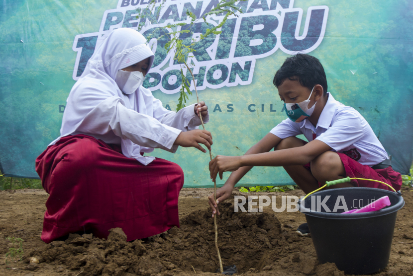 Dua siswa Sekolah Dasar menanam pohon saat penanaman 100 ribu pohon di bantaran Daerah Aliran Sungai (DAS) Cilamaya, Cilamaya Hilir, Blanakan, Subang, Jawa Barat, Sabtu (4/12/2021). 