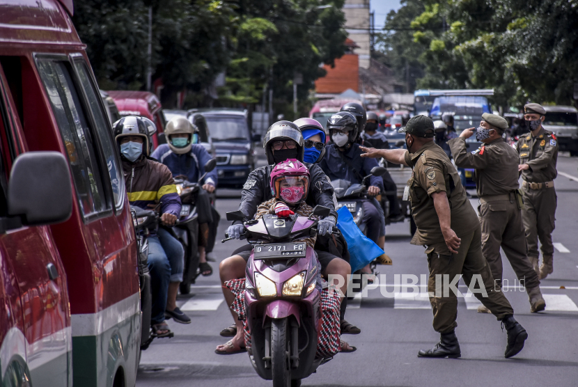 Petugas gabungan menghentikan pengendara yang tidak menggunakan masker saat operasi gabungan patroli pengawasan dan penegakan disiplin protokol kesehatan Covid-19 di Jalan Dalem Kaum, Kota Bandung. Ilustrasi
