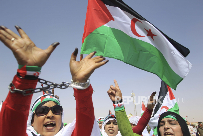  Pengungsi wanita dari Sahara Barat mengibarkan bendera tidak resmi mereka selama parade militer yang menandai peringatan 45 tahun pembentukan Republik Demokratik Arab Sahrawi (SARD), Sabtu, 27 Februari 2021 di sebuah kamp pengungsi dekat Tindouf, Aljazair selatan. Perserikatan Bangsa-Bangsa mengupayakan penyelesaian konflik di Sahara Barat setelah penarikan Spanyol pada tahun 1976 dari wilayah tersebut, yang diklaim oleh Maroko dan SADR.