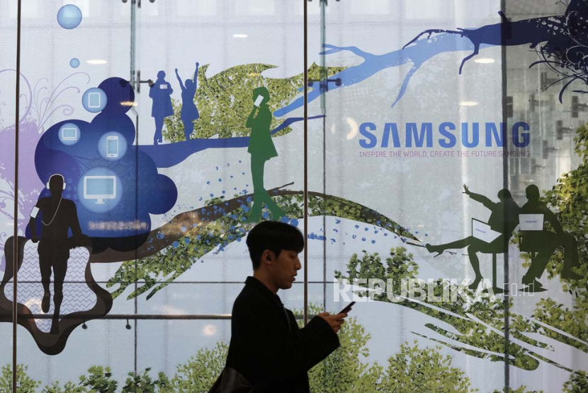 Seorang pria melewati logo Samsung Electronics. 