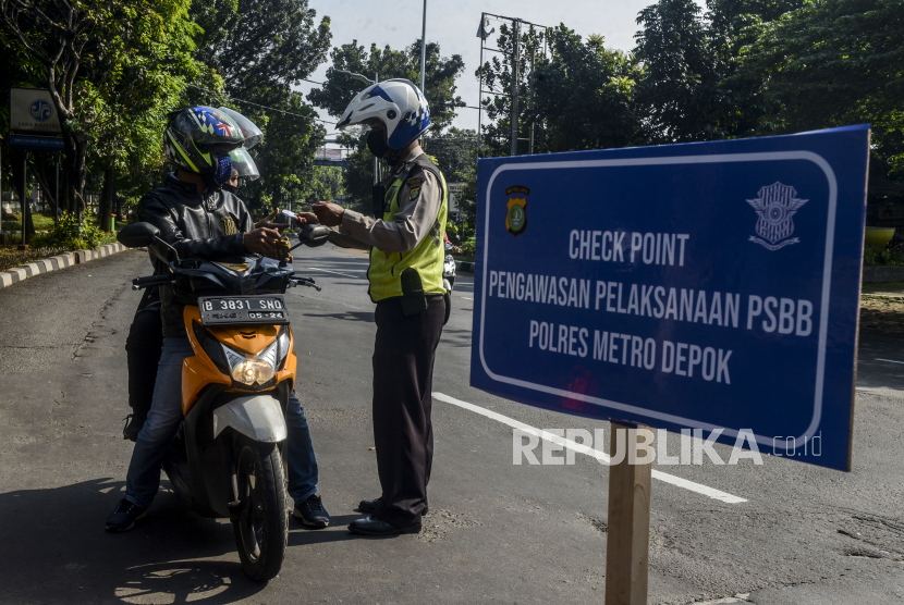 Polisi memeriksa identitas pengendara motor di perbatasan Jakarta dan Depok, Lenteng Agung, Jakarta Selatan. 