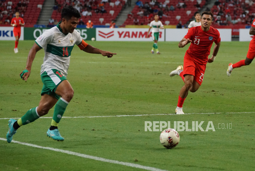 Pesepak bola Timnas Indonesia Asnawi Mangkualam (kiri) berusaha melewati hadangan pesepak bola Timnas Singapura Zulfahmi Arifin (kanan) dalam pertandingan Semi Final Leg 1 Piala AFF 2020 di National Stadium, Singapura, Rabu (22/12/2021).  