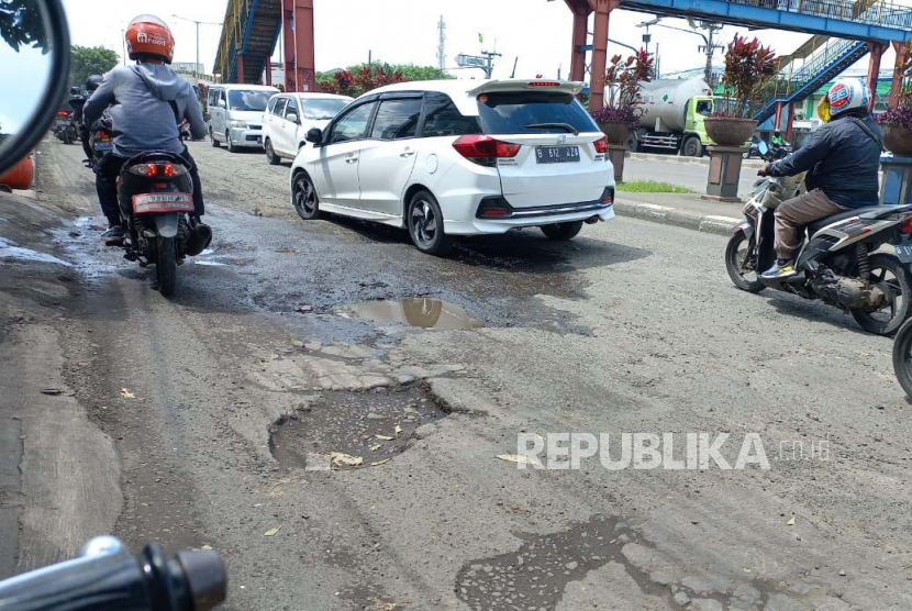 Kendaraan roda empat dan dua melintas perlahan di  Jalan Jendral Sudirman, Kranji, tepatnya di Gg Banteng, Senin (6/3/2023). Setiap kendaraan yang melintas jalur ini harus mengurangi kecepatannya karena jalan sudah rusak parah. 