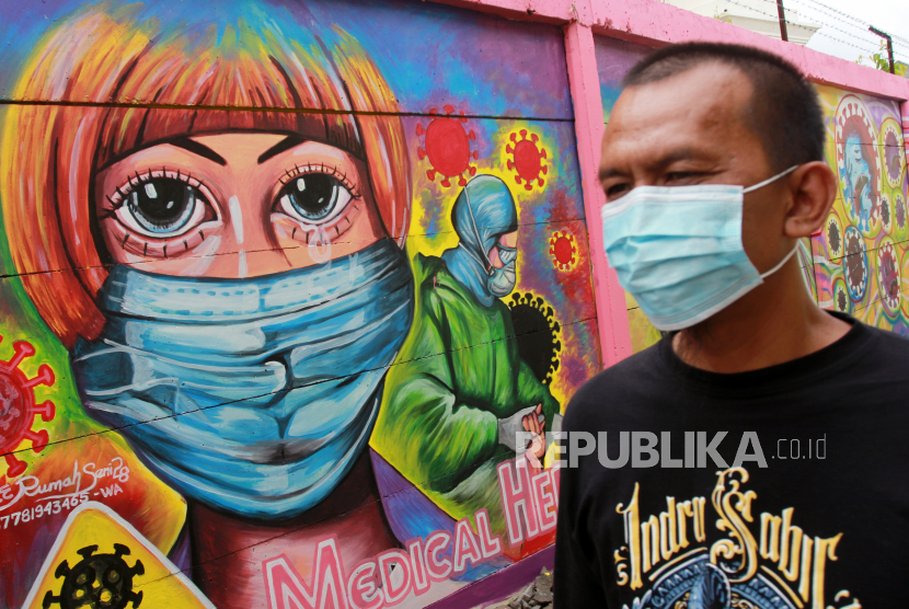 Warga melintas disamping mural yang bertemakan kampanye melawan COVID -19 yang ada di kawasan Tanah Tinggi, Tangerang, Banten, Rabu (20/1/2021). Kampanye dalam bentuk mural melawan COVID-19 tersebut merupakan bagian dari edukasi bagi masyarakat untuk lebih meningkatkan kewaspadaan terhadap pandemi itu. 