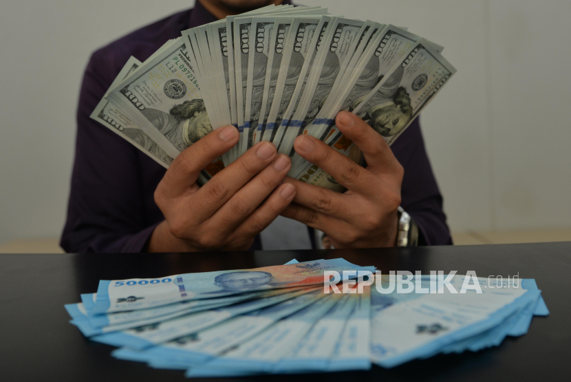 Teller menghitung uang dolar AS di kantor cabang Bank Muamalat Bintaro Jaya, Tangerang Selatan.