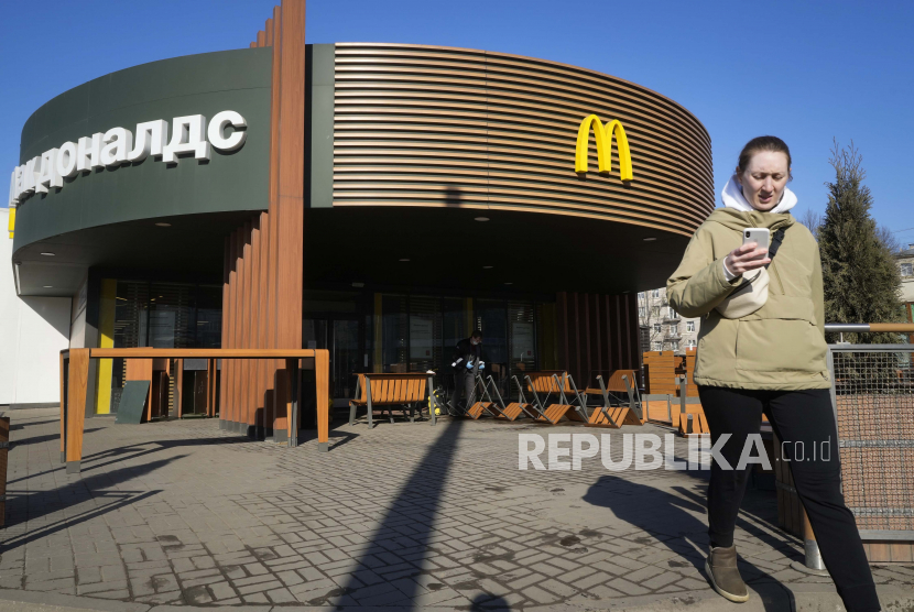 Seorang wanita berjalan melewati restoran McDonalds di St. Petersburg, Rusia. Setelah menutup gerai di Rusia, McDonalds memutuskan pergi dari Rusia akibat invasi.