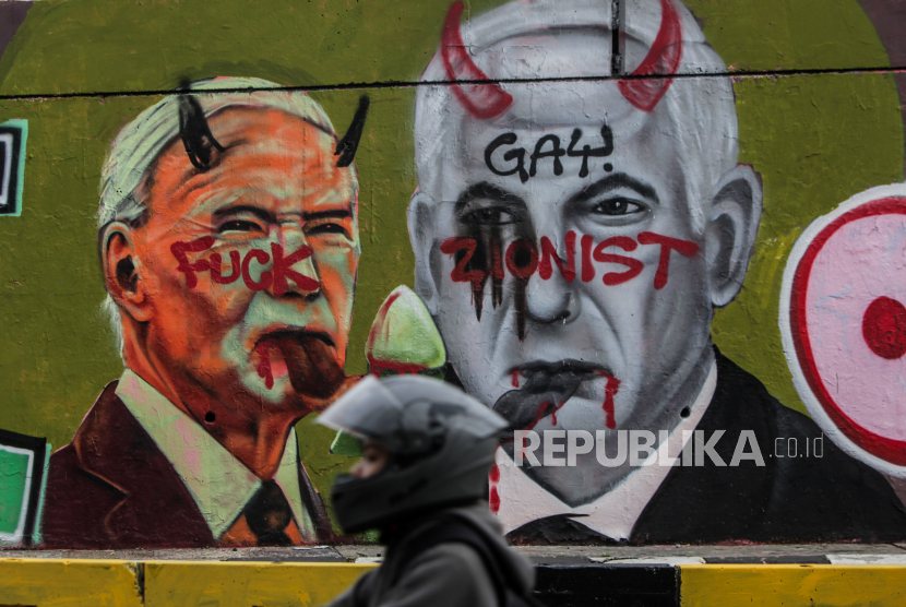 Pengendara motor melintas di dekat mural wajah Perdana Menteri Israel Benjamin Netanyahu dan Presiden Amerika Serikat Joe Biden di Grogol, Jakarta, Senin (3/6/2024).
