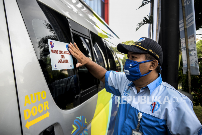 Petugas saat menempelkan imbauan memakai masker dan jaga jarak pada armada The All New Mikrotrans saat peluncuran di Kantor Pusat Transjakarta. SPTJ menyebut masalah konflik Transjakarta dan pekerja berkembang liar