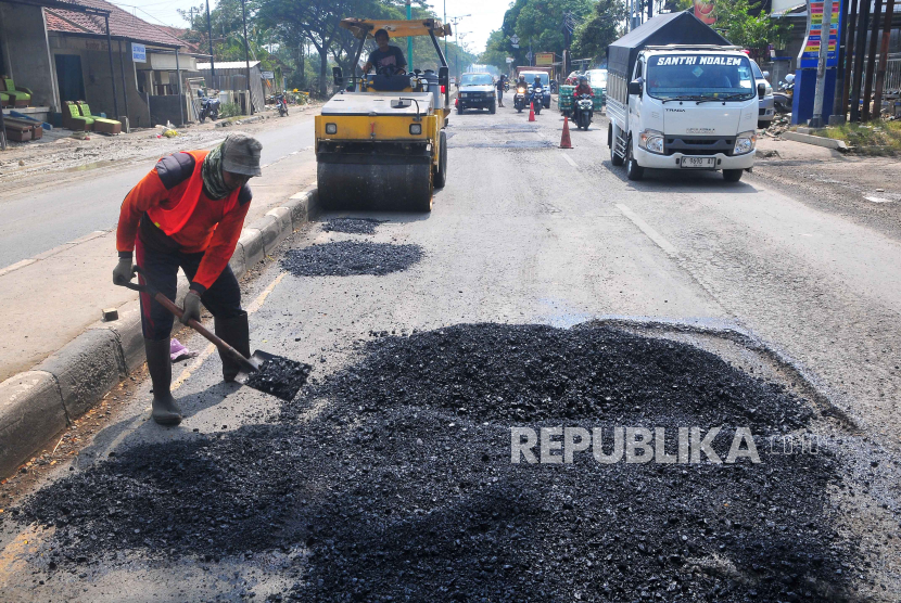 Pekerja memperbaiki ruas jalan yang rusak akibat banjir di jalur pantura wilayah Karanganyar, Kabupaten Demak, Jawa Tengah, Senin (25/3/2024). 