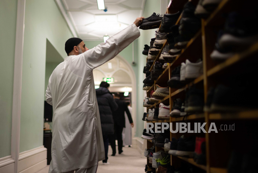 Umat muslim menaruh alas kaki memasuki masjid saat akan mengikuti buka puasa bersama di Masjid Rawdah di Bradford, Inggris, Ahad (9/4/2023).