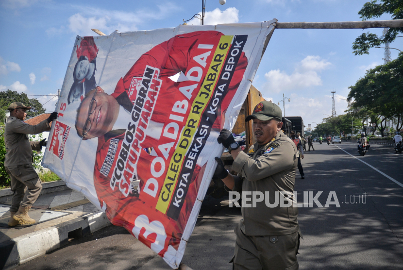 Petugas Satpol PP mencopot Alat Peraga Kampanye (APK) yang masih terpasang di Kawasan Jalan Margonda, Depok, Jawa Barat, Ahad (11/2/2024). 