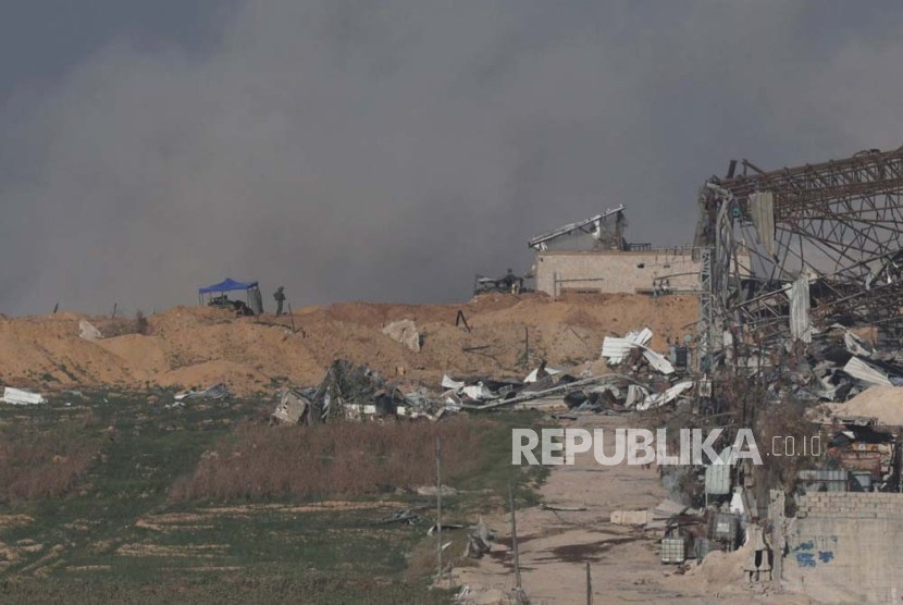Pasukan Israel dalam posisi ketika asap membubung di atas kamp pengungsi Buraij di Jalur Gaza tengah, terlihat dari lokasi yang dirahasiakan di Israel (10/1/2024).
