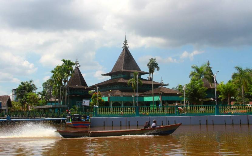 Perahu bermesin (kelotok) melintas di Sungai Kuin berlatar Masjid Sultan Suriansyah, Banjarmasin, Kalimantan Selatan. 