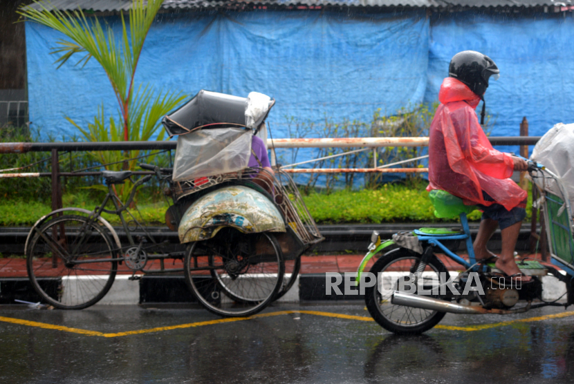 Tukang becak motor menggunakan ponco saat hujan di kawasan Ngabean, Yogyakarta.